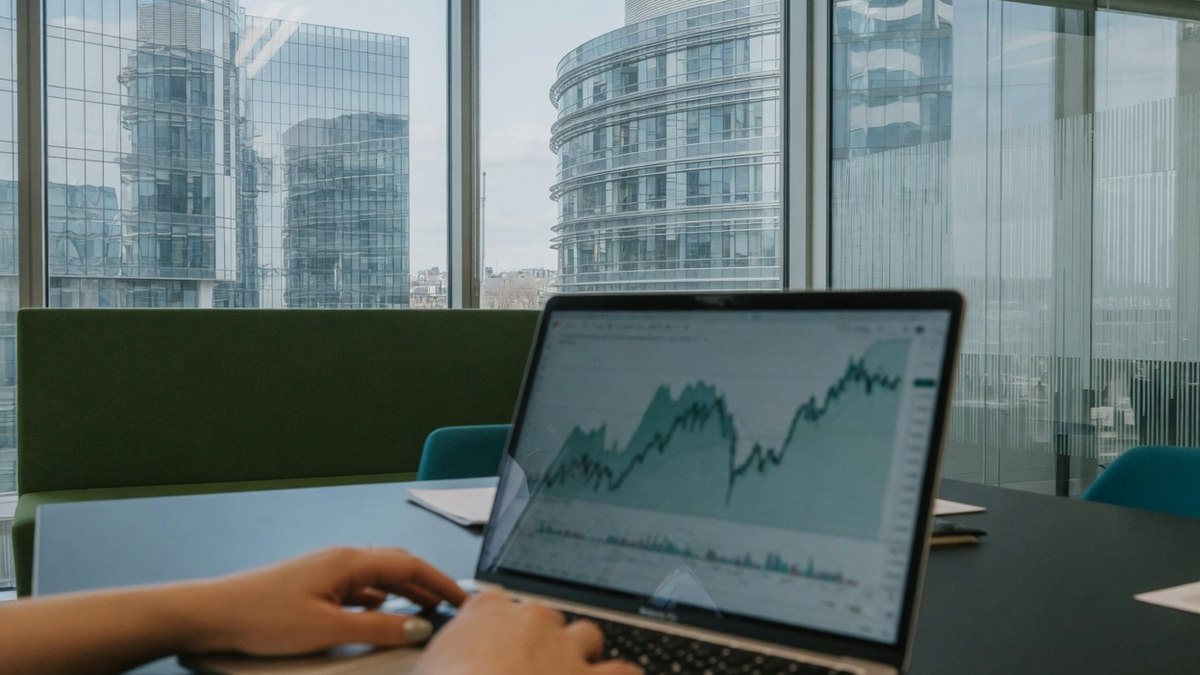 Bureaux modernes avec écrans affichant des graphiques financiers, mains sur un clavier, ambiance sobre B2B